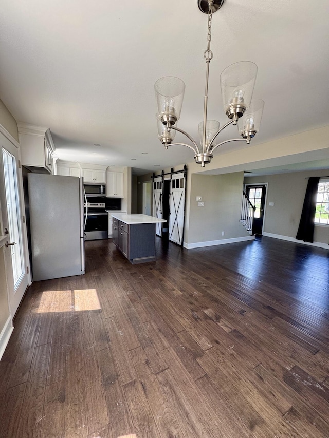 kitchen featuring an inviting chandelier, open floor plan, a center island, a barn door, and appliances with stainless steel finishes