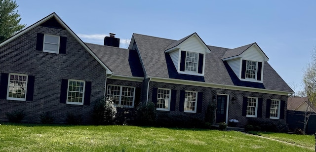 cape cod home with a front yard, brick siding, and a chimney