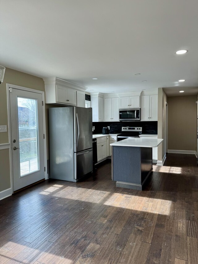 kitchen featuring a kitchen island, appliances with stainless steel finishes, dark wood-style flooring, light countertops, and white cabinetry