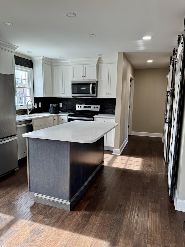 kitchen featuring a barn door, a kitchen island, white cabinets, light countertops, and appliances with stainless steel finishes