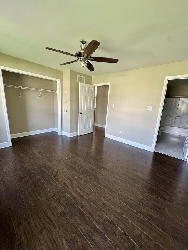 unfurnished bedroom featuring dark wood-style flooring, a closet, baseboards, and visible vents