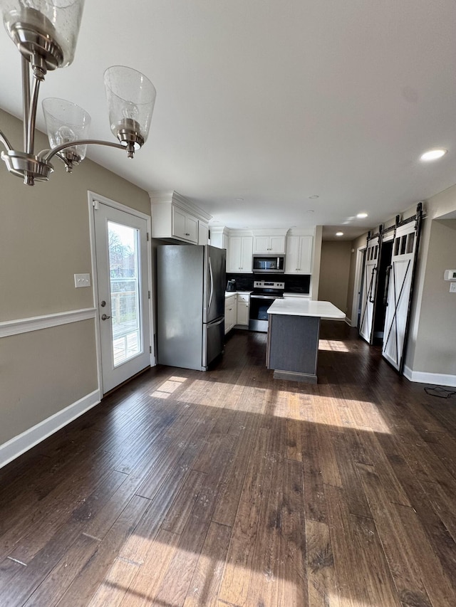 kitchen with a barn door, white cabinets, a kitchen island, stainless steel appliances, and light countertops