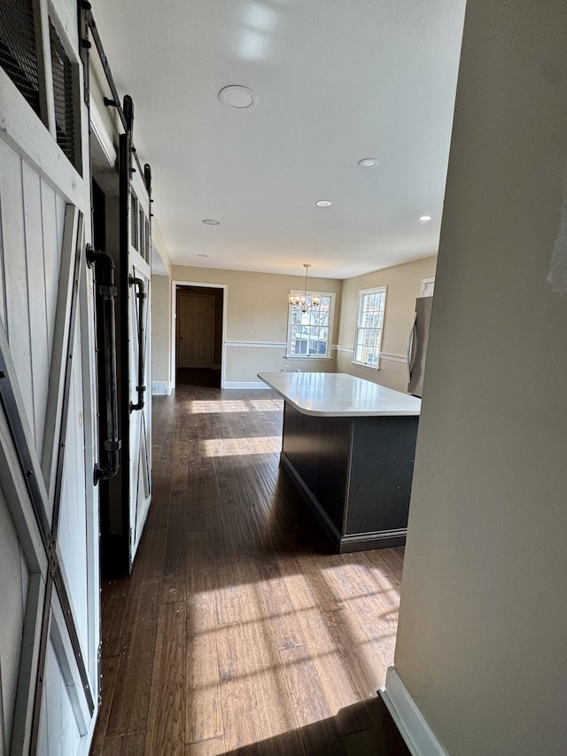 kitchen featuring a barn door, freestanding refrigerator, hanging light fixtures, a center island, and light countertops