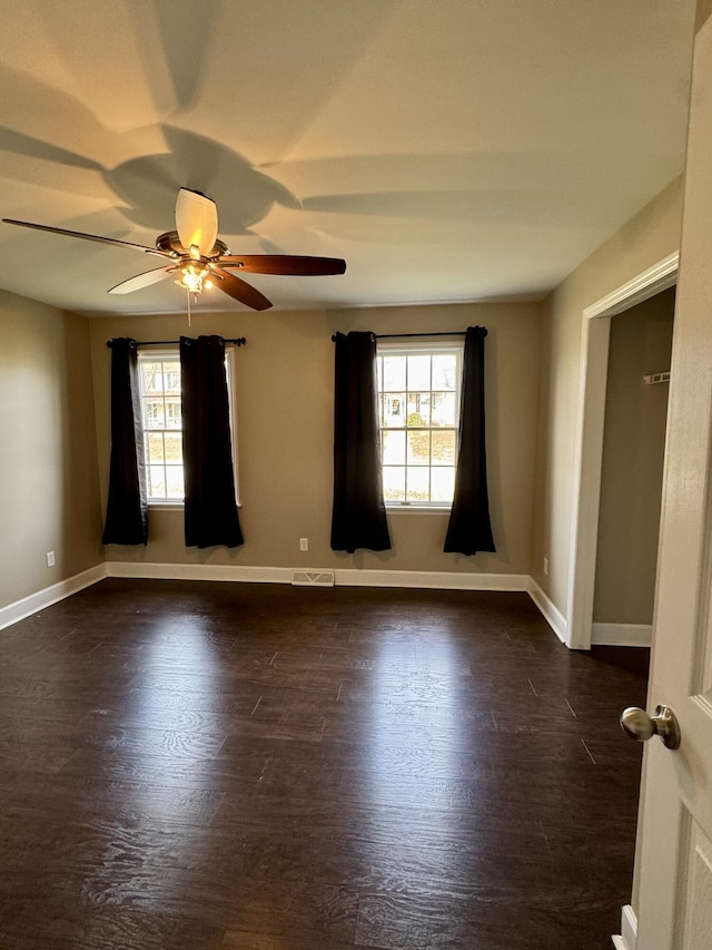 unfurnished room featuring plenty of natural light, dark wood finished floors, and baseboards