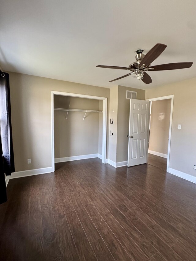 unfurnished bedroom featuring a closet, dark wood finished floors, visible vents, and baseboards