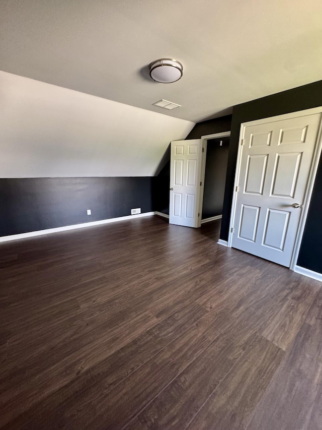 bonus room with visible vents, baseboards, vaulted ceiling, and dark wood finished floors