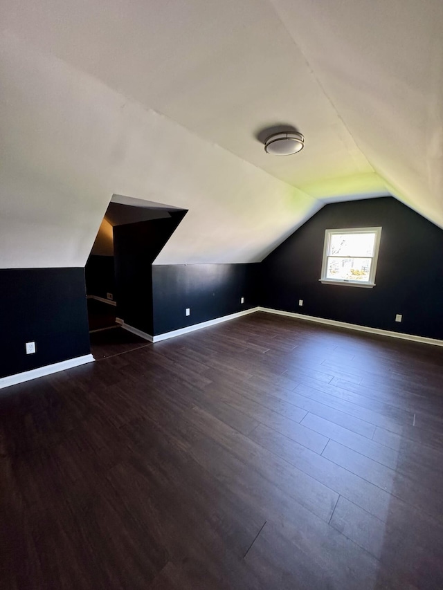 bonus room featuring dark wood-style floors, baseboards, and vaulted ceiling