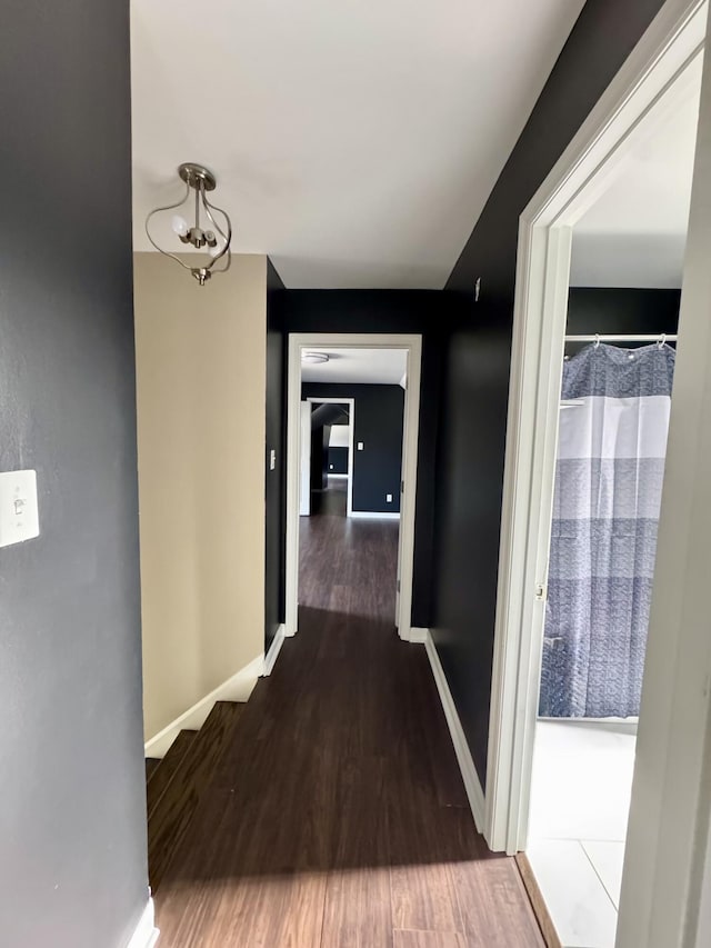 hallway featuring baseboards and wood finished floors