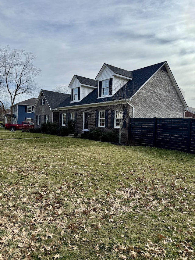 view of front of home with a front yard, brick siding, and fence