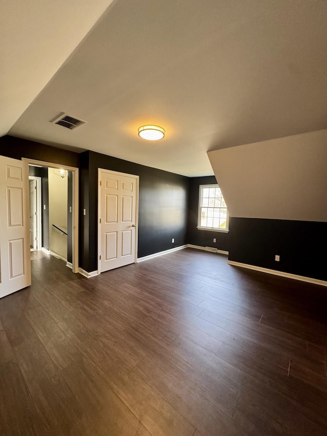 interior space with lofted ceiling, baseboards, visible vents, and dark wood finished floors