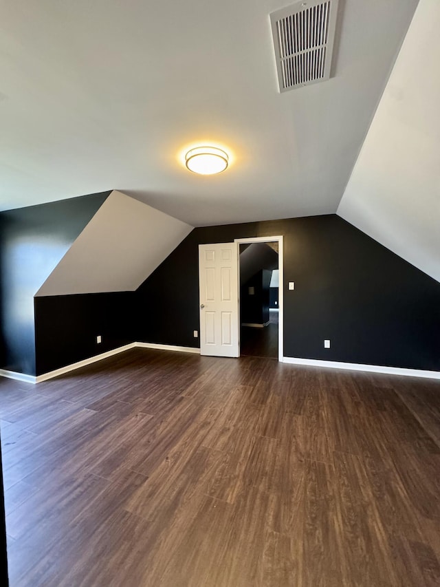 additional living space featuring vaulted ceiling, dark wood finished floors, visible vents, and baseboards