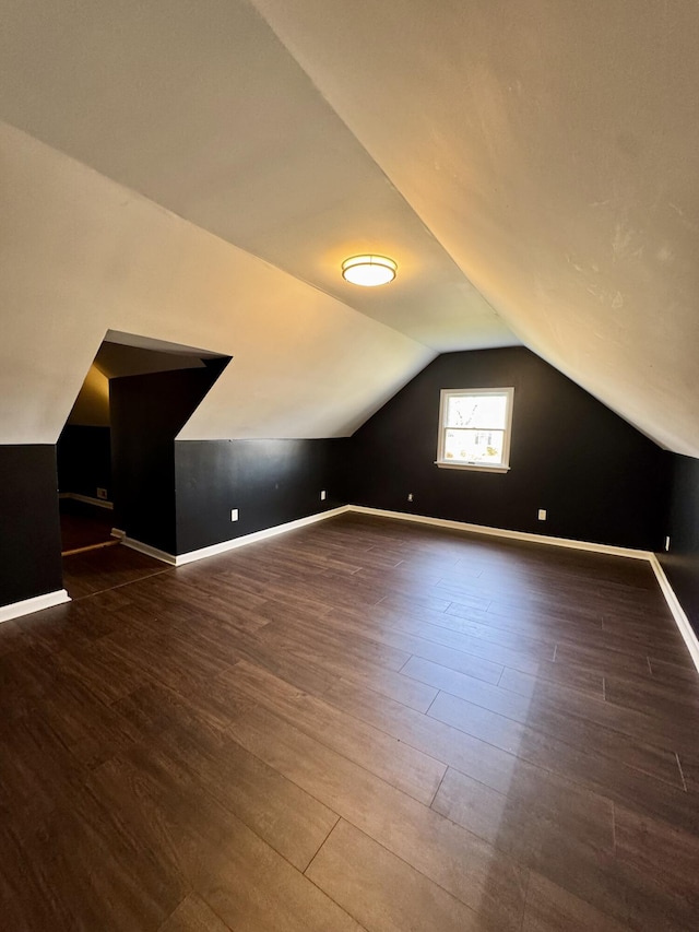 additional living space featuring lofted ceiling, dark wood finished floors, and baseboards