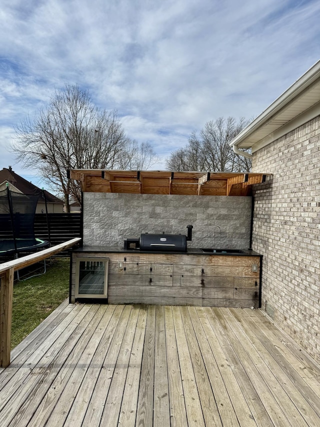 wooden deck with a trampoline and area for grilling