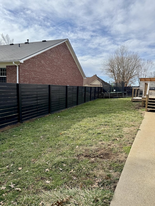 view of yard featuring a trampoline and a fenced backyard