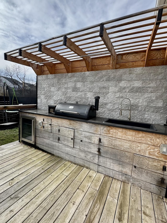 wooden deck featuring a sink, a grill, a pergola, and area for grilling