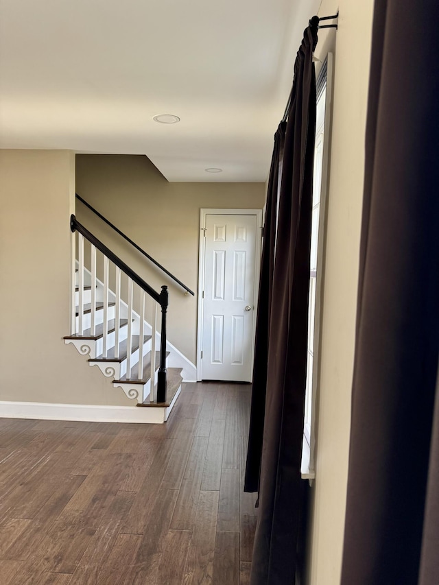 corridor with stairs, dark wood finished floors, and baseboards