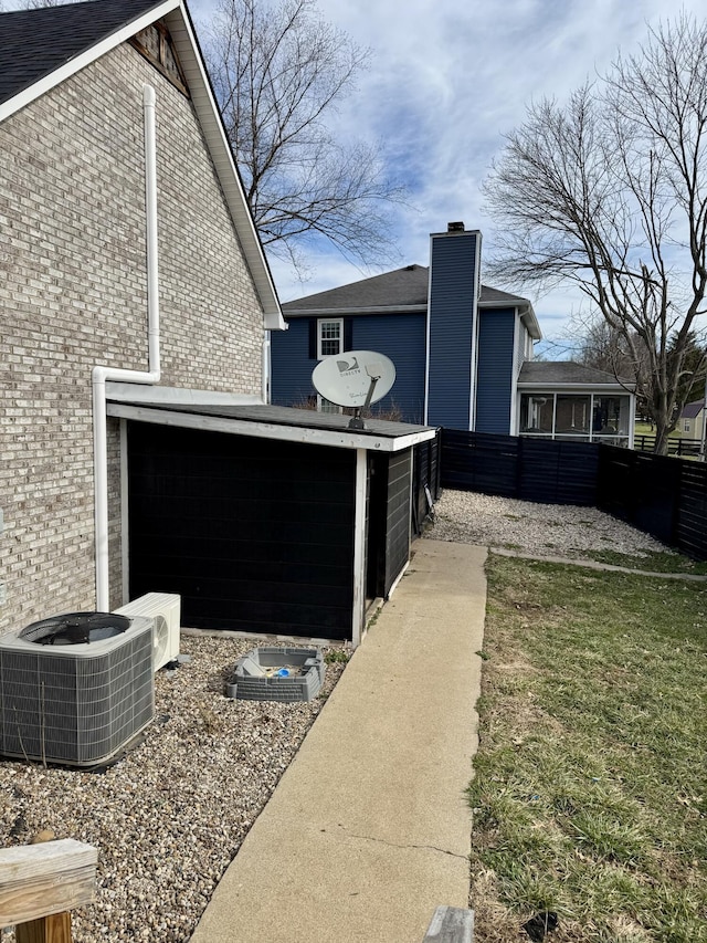 view of property exterior featuring brick siding, cooling unit, and fence