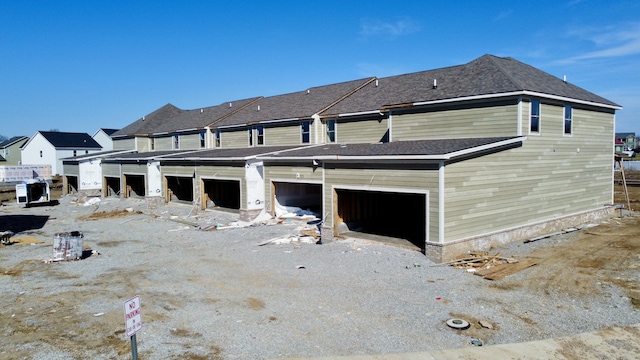 rear view of property with dirt driveway and a garage