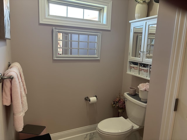 half bath with marble finish floor, baseboards, and toilet