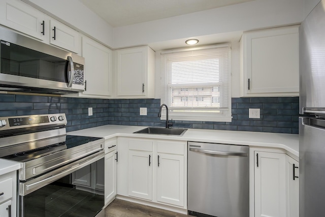 kitchen with stainless steel appliances, a sink, white cabinets, light countertops, and decorative backsplash