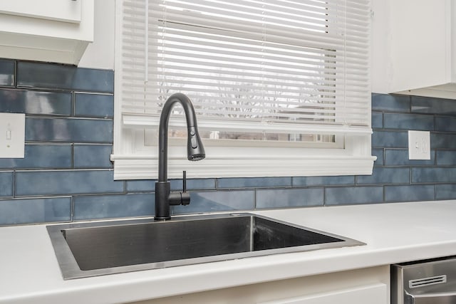 interior details featuring white cabinets, decorative backsplash, a sink, and light countertops