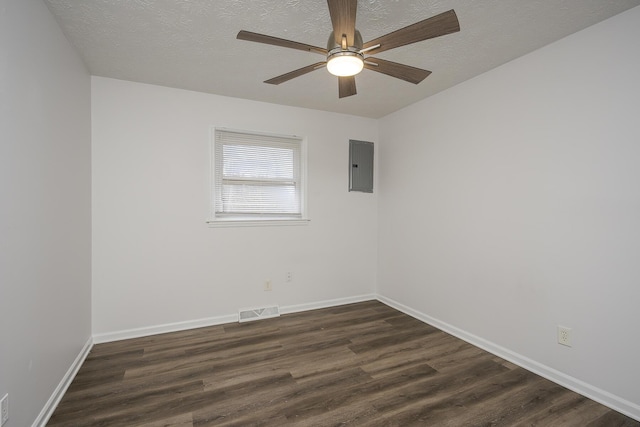 spare room featuring a textured ceiling, electric panel, visible vents, and dark wood-type flooring