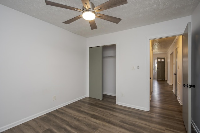 unfurnished bedroom with dark wood-style floors, a textured ceiling, and baseboards