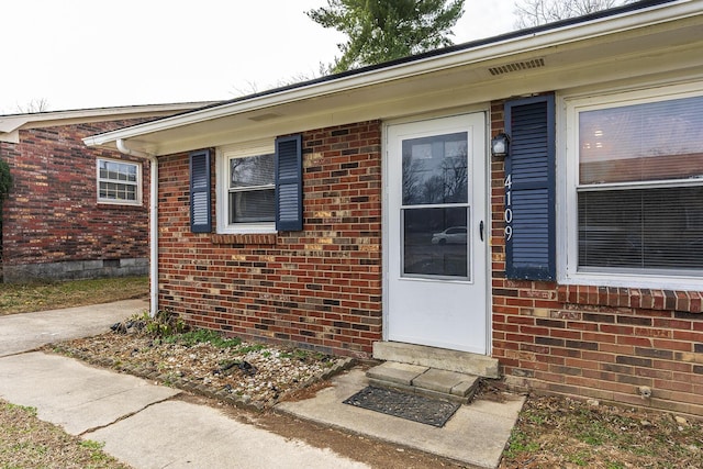 property entrance featuring crawl space and brick siding