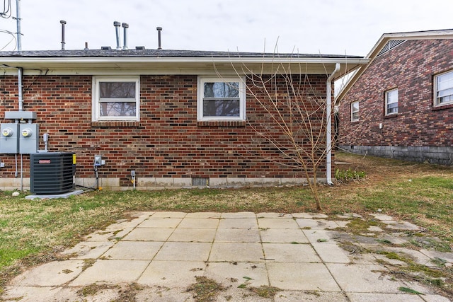 back of house with central air condition unit, a patio, and brick siding