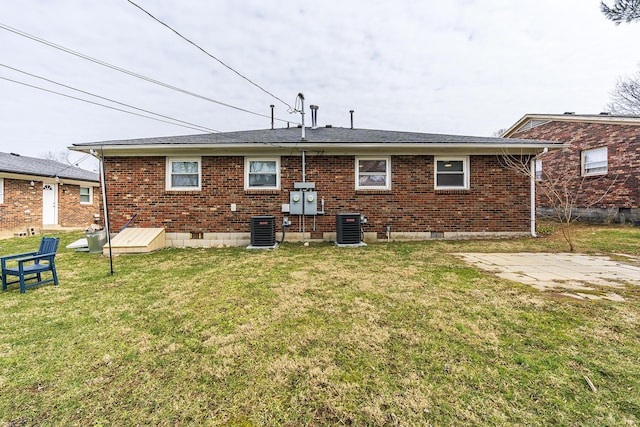 rear view of house with central AC, brick siding, crawl space, and a lawn