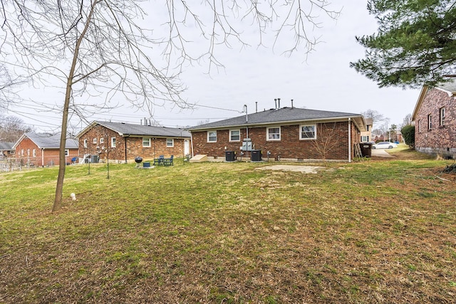 back of property with a yard, cooling unit, and brick siding