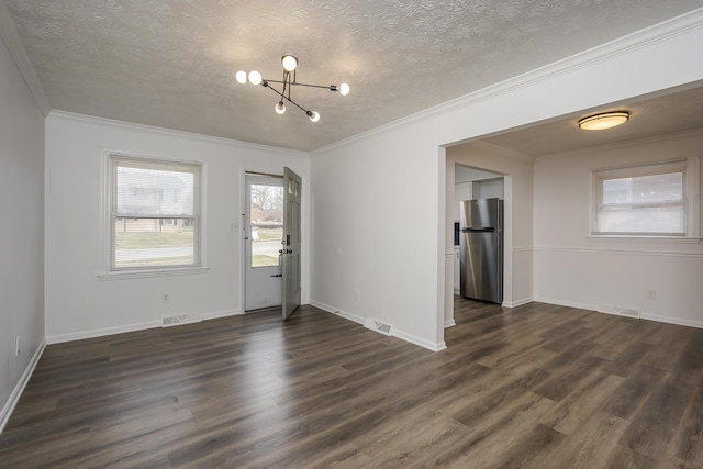 spare room featuring dark wood-style floors, visible vents, ornamental molding, and a textured ceiling