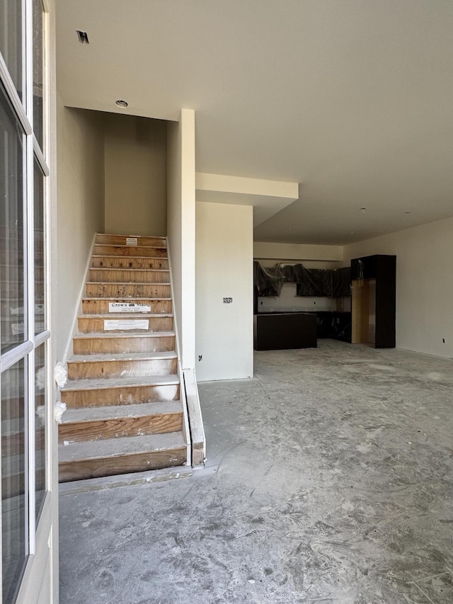 staircase featuring unfinished concrete floors