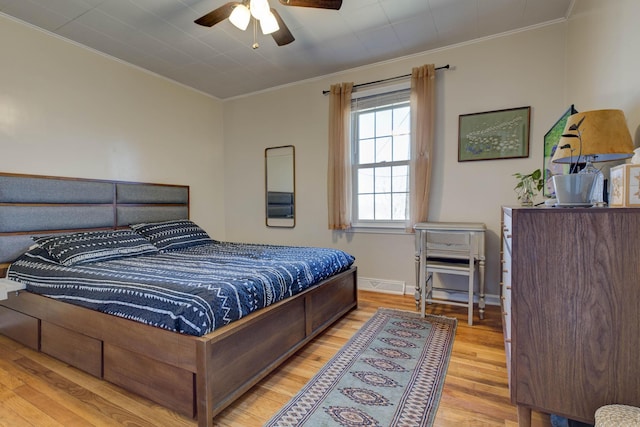 bedroom with baseboards, wood finished floors, visible vents, and crown molding