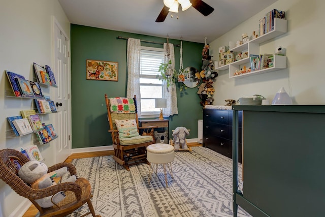 sitting room with ceiling fan and baseboards