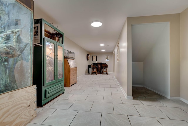 corridor with light tile patterned floors and baseboards