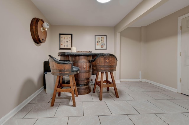 bar featuring a dry bar, tile patterned flooring, and baseboards