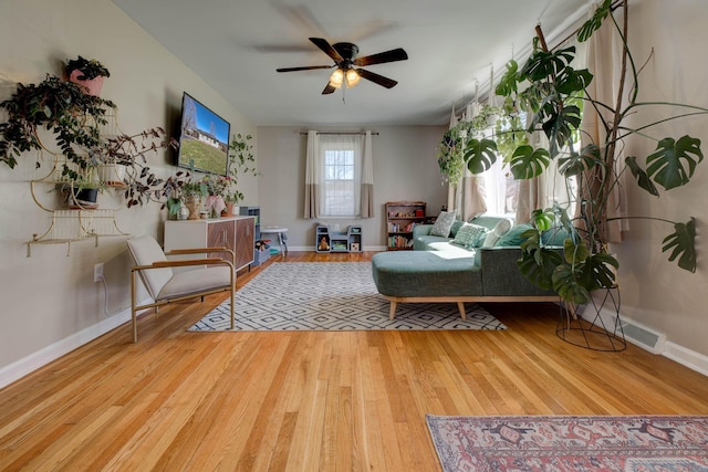 living area with a ceiling fan, baseboards, and wood finished floors