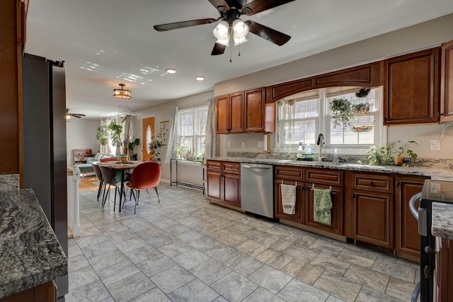 kitchen with stainless steel dishwasher, stove, a ceiling fan, a sink, and light stone countertops