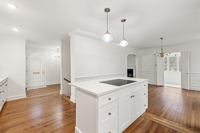 kitchen featuring wood-type flooring, an inviting chandelier, black electric cooktop, light countertops, and white cabinetry