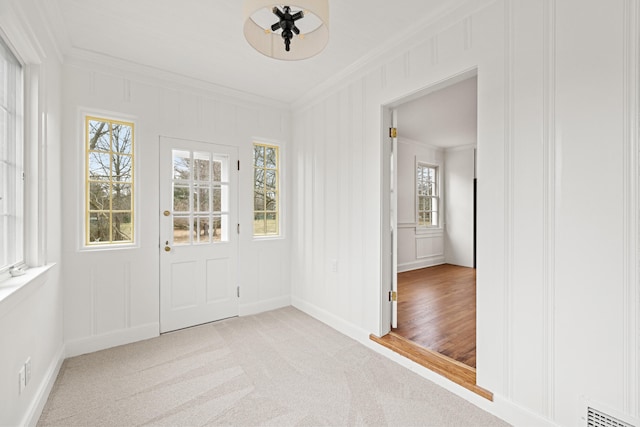 interior space featuring visible vents, ornamental molding, a decorative wall, and light colored carpet