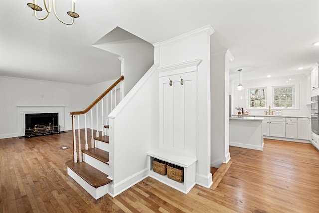 staircase with a fireplace with flush hearth, baseboards, and wood finished floors