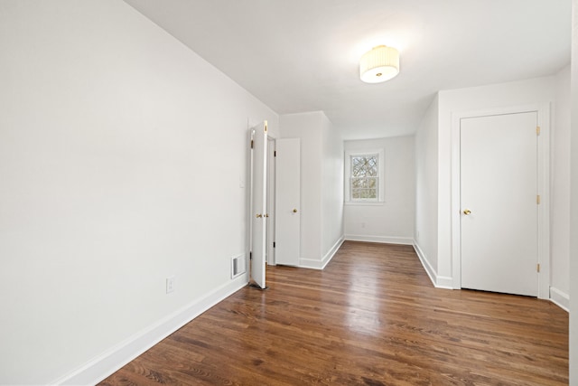 empty room featuring visible vents, baseboards, and wood finished floors