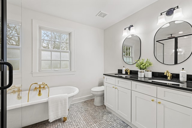 full bath with a freestanding bath, double vanity, a sink, and visible vents