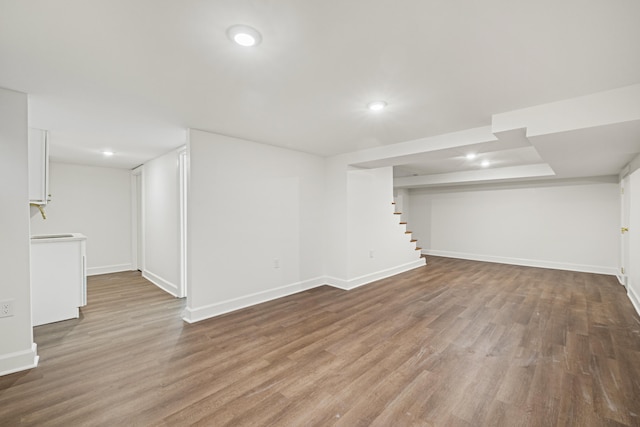 finished basement with stairway, baseboards, wood finished floors, and recessed lighting