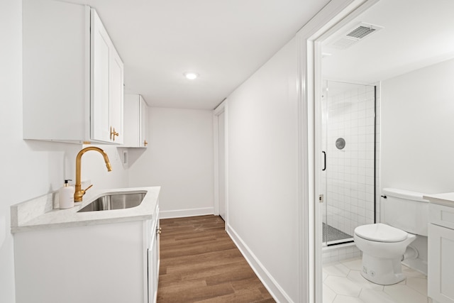 interior space with wood finished floors, a sink, visible vents, white cabinetry, and light countertops