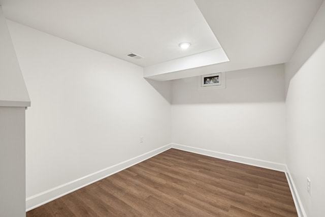 spare room with dark wood-style floors, visible vents, and baseboards