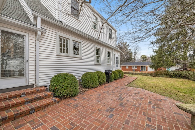 view of side of home featuring a yard and roof with shingles