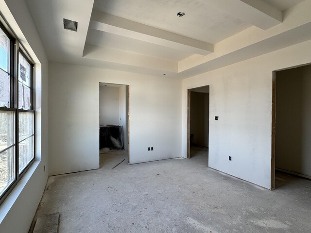 unfurnished bedroom with multiple windows and a tray ceiling