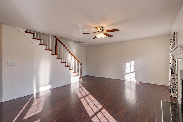 unfurnished living room featuring ceiling fan, stairway, wood finished floors, and crown molding